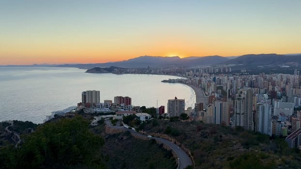A breathtaking panoramic sunset scene over the coastal city of Benidorm, showcasing its vibrant, stunning colors