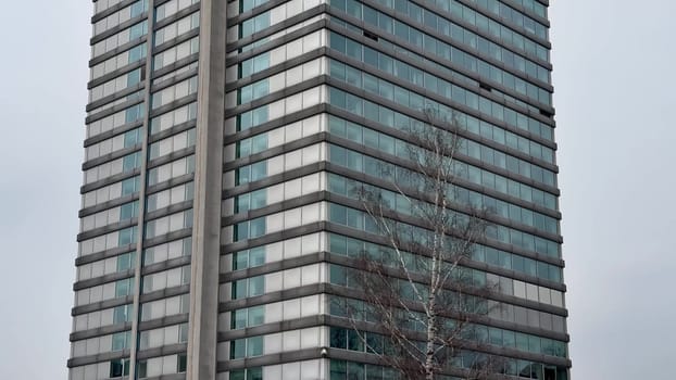 A contemporary office tower showcasing a sleek and stunning glass design positioned dramatically against a gray sky