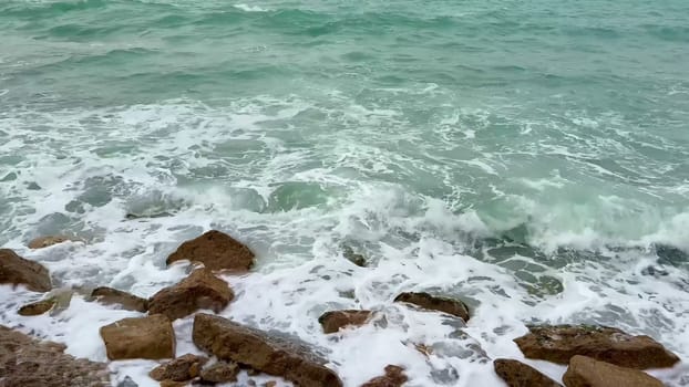 Witness the serene beauty of powerful waves crashing against rugged rocks, showcasing natures artistic power