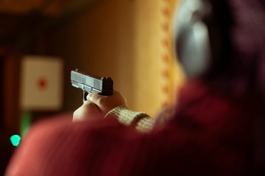 Woman in firing range doing recreational shooting activity with firearm, hitting bullseyes. Close up of person in shooting gallery training with handgun, sharpening skills, developing muscle memory
