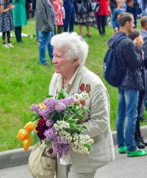 PYATIGORSK, RUSSIA - MAY 09, 2017: War veteran woman with flowers on the Victory Day celebration. Russian babushka