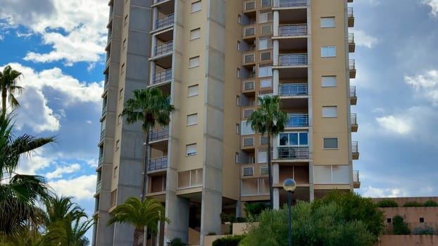 A stylish highrise building gracefully surrounded by palm trees against a stunning and dramatic cloudy backdrop