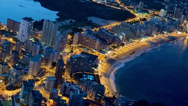 A breathtaking aerial view brilliantly showcasing the illuminated cityscape and stunning coastline at night