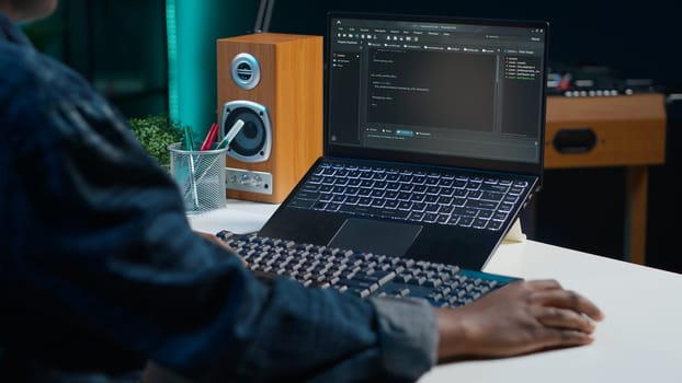 Teleworker in living room office using laptop to do coding for software developing, handheld camera shot. Remote employee typing on device keyboard, solving tasks in apartment, camera A close up