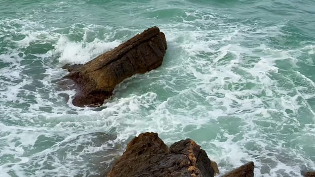 Capture the ocean waves splashing against a rocky shoreline, framed by vibrant turquoise waters reflecting sunlight