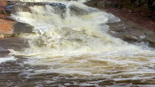 A stunning view of a magnificent waterfall cascading over rugged rocks, with foamy water flowing below