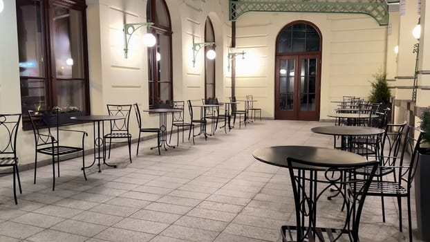 The cozy night view features empty outdoor cafe tables softly illuminated, enhancing the inviting atmosphere