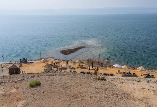 Dead Sea, Jordan - 8 November 2024: Tourists in the waters of Dead Sea by a beach in modern hotel