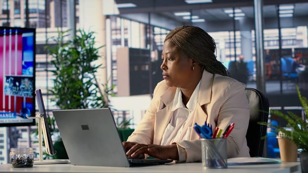 African american CEO driven by empowerment and ambition in her office, focuses on achieving business targets and enhancing company performance in a dynamic corporate setting. Success story. Camera A.