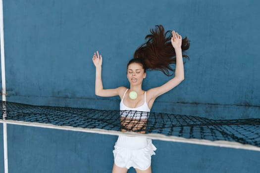 A young woman playfully floats in a pool with a tennis ball, dressed in a white swimsuit against a vibrant blue backdrop, embodying summer fun and relaxation