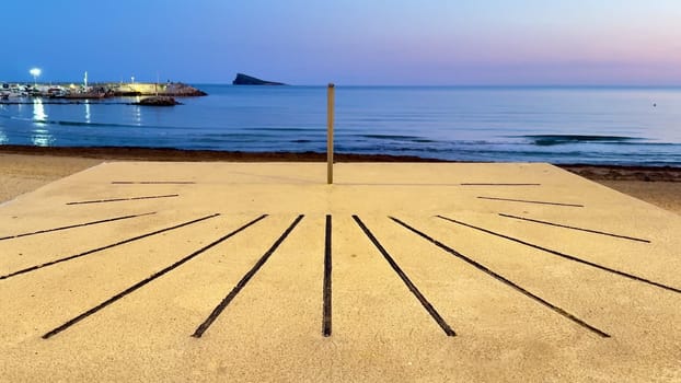 A serene beach sundial positioned at sunset, beautifully reflecting tranquility and calmness by the soothing sea