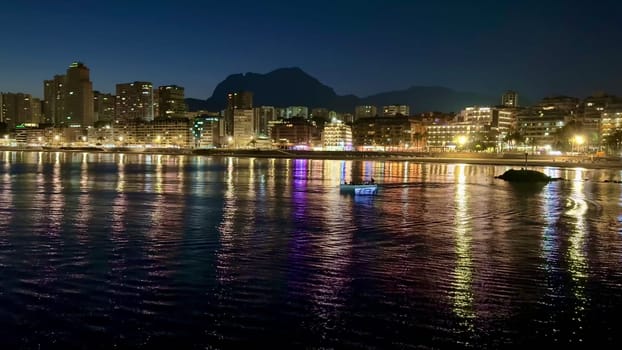 The stunning urban skyline at night showcases vibrant lights beautifully reflecting on the calm water surface