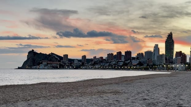 A breathtaking sunset casts vibrant hues over the enchanting coastal skyline and inviting sandy beach