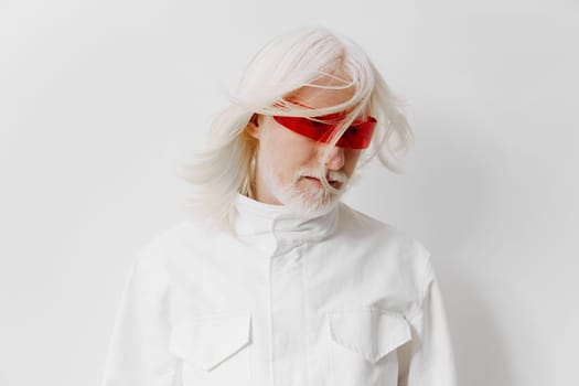 A fashionable elderly man with striking white hair and red tinted sunglasses, dressed in a white outfit against a clean white background, representing a blend of sophistication and contemporary style