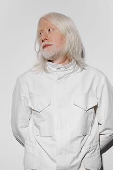 fashion, model, portrait of a man with long white hair and beard in a white coat against a plain white background, showcasing a minimalist style and reflective mood, perfect for artistic projects