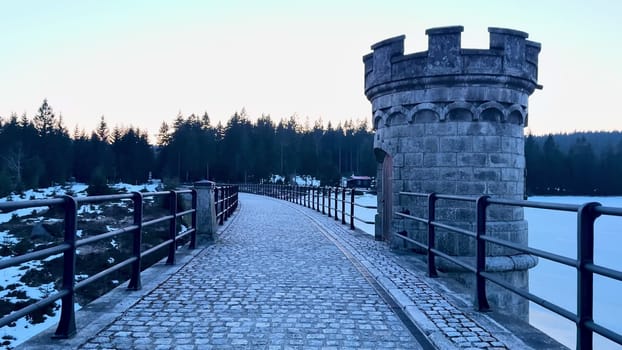 A beautifully serene winter landscape scene showcasing a frozen lake alongside a historic stone tower at dusk