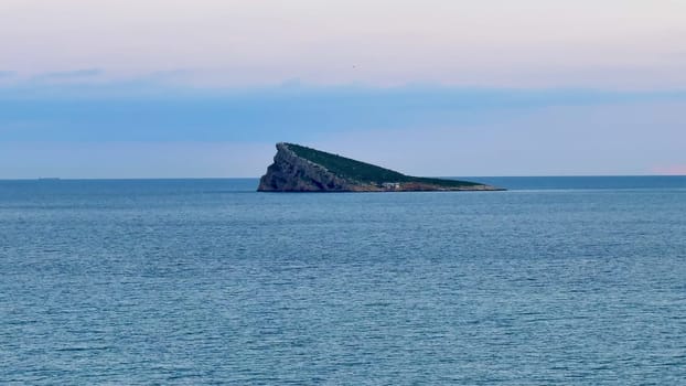 A stunning view of a distinctive island surrounded by calm, tranquil ocean waters during the beautiful dusk hour