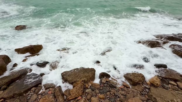 The beautiful waves elegantly crash on the rocky shores, showcasing the breathtaking power and tranquility of nature