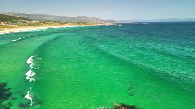 Breathtaking aerial shots showcasing turquoise waves gracefully rolling onto a pristine sandy beach under a clear sky