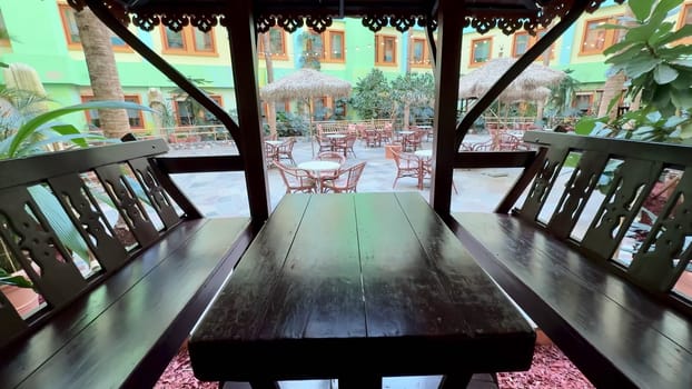 A serene and tranquil outdoor dining area that features cozy wooden seating amidst vibrant and lush surroundings