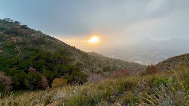 A stunning view of a breathtaking sunset that beautifully illuminates a mountainous coastline along with the serene sea
