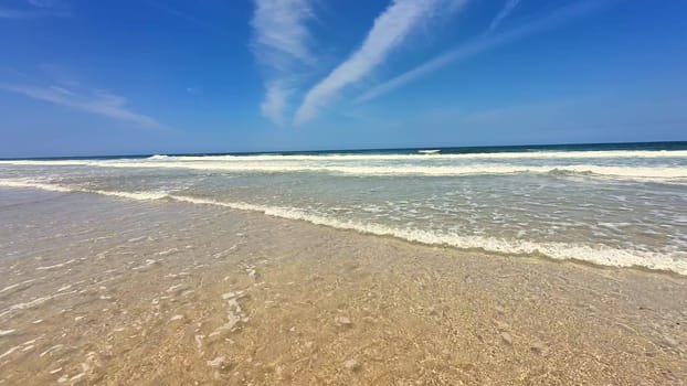 A serene beach scene, showcasing the clear, inviting waters beneath a bright, limitless blue sky overhead