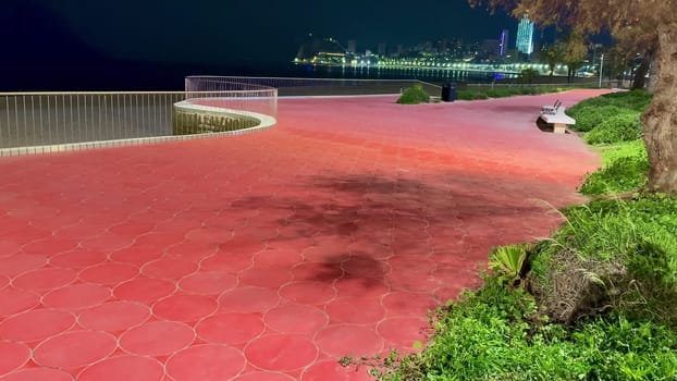 A serene waterfront pathway with stunning skyline views at night, perfect for relaxation and strolls