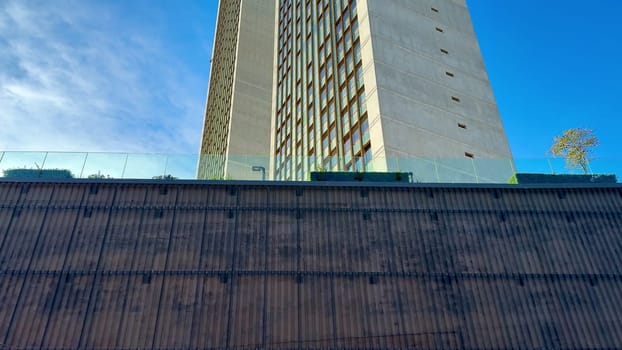 A breathtaking view of a modern contemporary skyscraper extending high into the clear, vibrant blue sky