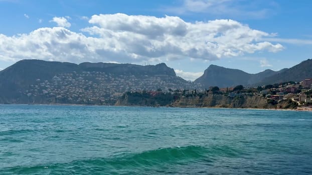 A beautiful coastline with clear water, majestic mountains, and a vibrant sky, ideal for relaxation and travel