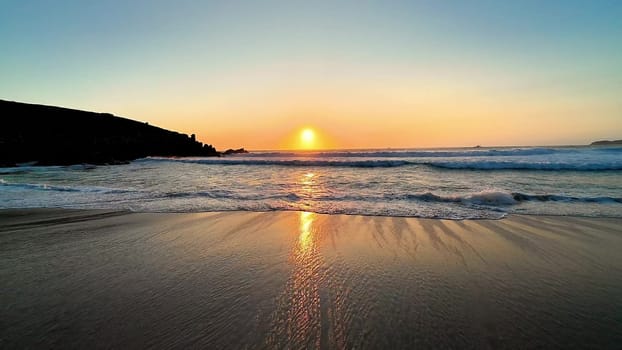 A breathtaking view of the sunset reflecting beautifully on the calm, still waters, creating a serene beachscape