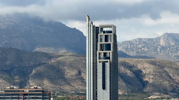 A breathtaking and stunning view of a sleek, modern skyscraper beautifully nestled amid majestic mountains