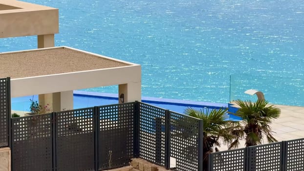 A beautiful landscape with a stunning infinity pool overlooking the ocean, enhanced by swaying palm trees
