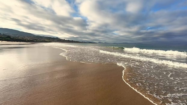 A beautiful and serene beach landscape that showcases gentle, rolling waves and an incredibly picturesque cloudy sky