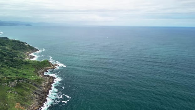 Aerial footage captures the stunning coastline with impressive cliffs, lush greenery, and serene waters