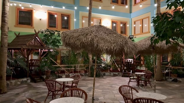 A charming courtyard features thatched umbrellas, tropical plants, and inviting seating for everyone