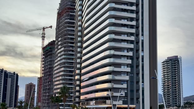 A dynamic cityscape showcasing modern highrises along with active construction work as dusk approaches softly