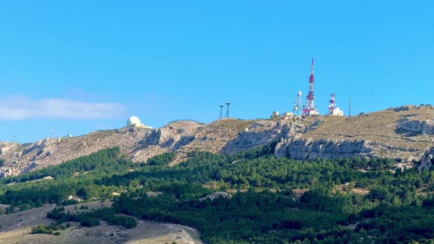 A stunning and beautiful landscape showcases communication towers perched atop a lush, green mountain slope