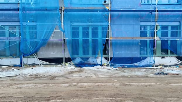 A bustling construction site showcasing blue safety netting and scaffolding diligently protecting the building