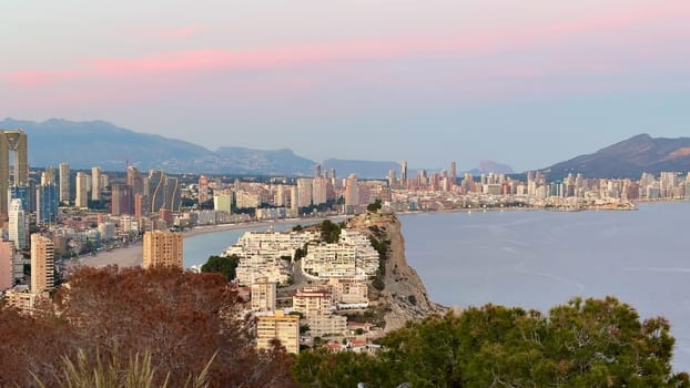 A captivating sunset view over the coastal city of Benidorm, showcasing its skyline and serene waters.