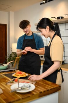 Cheerful young couple preparing to serve pancakes topped with strawberries.