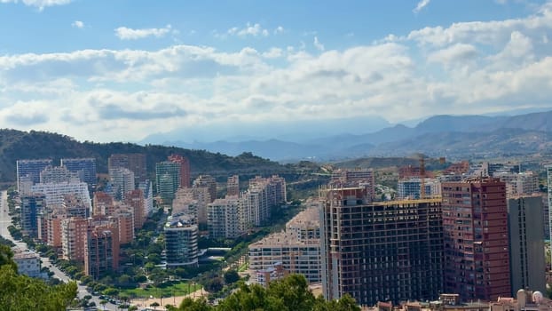 A breathtaking view showcasing a modern cityscape intricately surrounded by picturesque mountains and wispy clouds