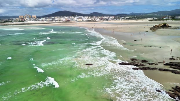 The breathtaking beach scenery features vibrant green waters gently lapping at the shore beneath a clear blue sky