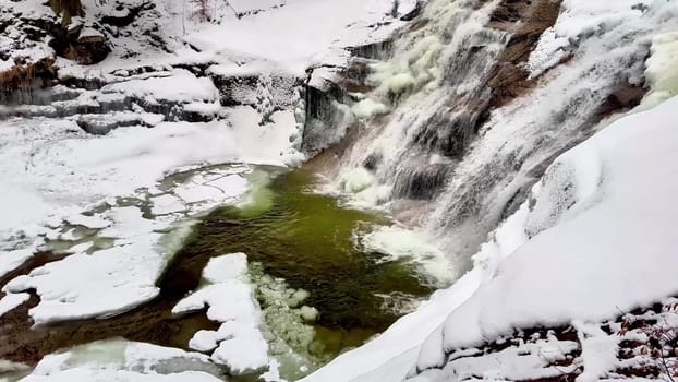 A stunning winter scene showcasing a majestic cascading waterfall, beautifully surrounded by snow and ice