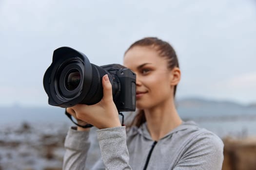 Inspired female photographer in sporty attire focuses on capturing nature with her camera, highlighting creativity and dedication in an outdoor environment