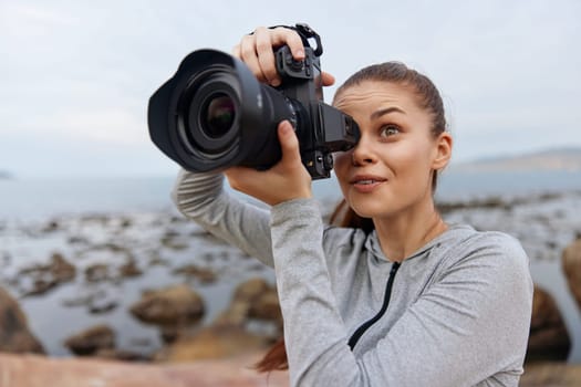 Captivating portrait of a young woman photographer enjoying the seaside, displaying joy and enthusiasm, dressed in casual outdoor attire, ready to capture stunning landscapes