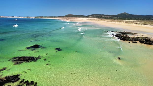 An aerial photograph captures a picturesque beach scene with vibrant turquoise waters and inviting soft sandy shores