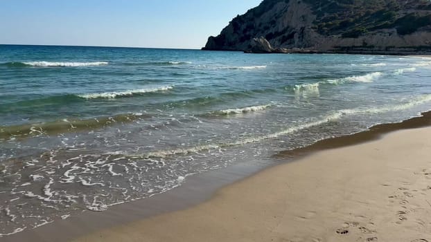 Experience the soothing tranquility of soft waves gently lapping on a sandy beach under a clear blue sky