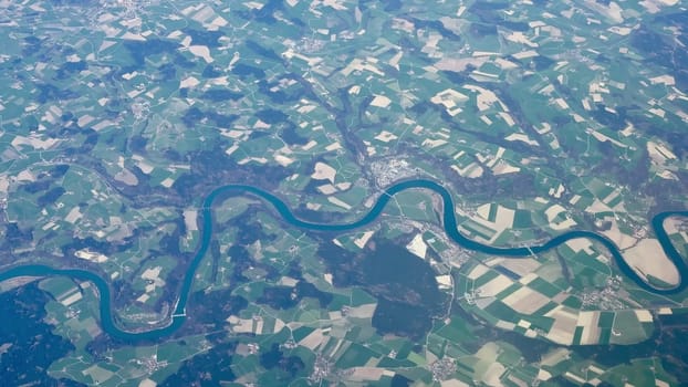 A stunning aerial photograph beautifully showcases an elegantly winding river that flows amidst lush green fields