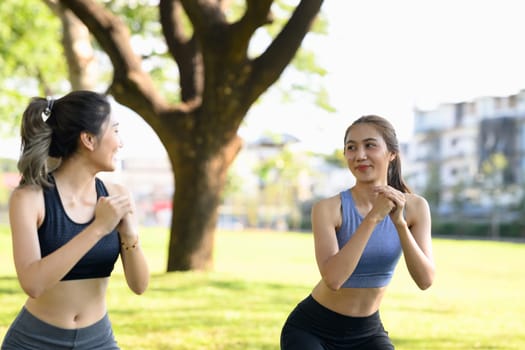 Fit Asian women in sportswear working out together in nature.
