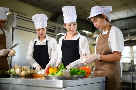 Cooking school instructor explaining food preparation techniques to students in a kitchen.